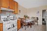 Kitchen featuring white gas range, under cabinet range hood, light countertops, backsplash, and light tile patterned flooring