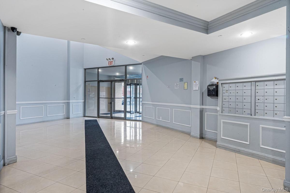 Lobby with a decorative wall, crown molding, and a wainscoted wall