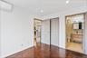 Unfurnished bedroom featuring a wall mounted AC, stainless steel fridge with ice dispenser, dark wood finished floors, connected bathroom, and recesse