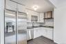 Kitchen featuring appliances with stainless steel finishes, white cabinets, dark stone countertops, wall chimney range hood, and backsplash
