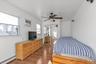Bedroom with a baseboard radiator, ceiling fan, light wood-style floors, a closet, and a wall unit AC