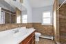 Bathroom featuring tiled shower, tile walls, a baseboard radiator, vanity, and a wainscoted wall