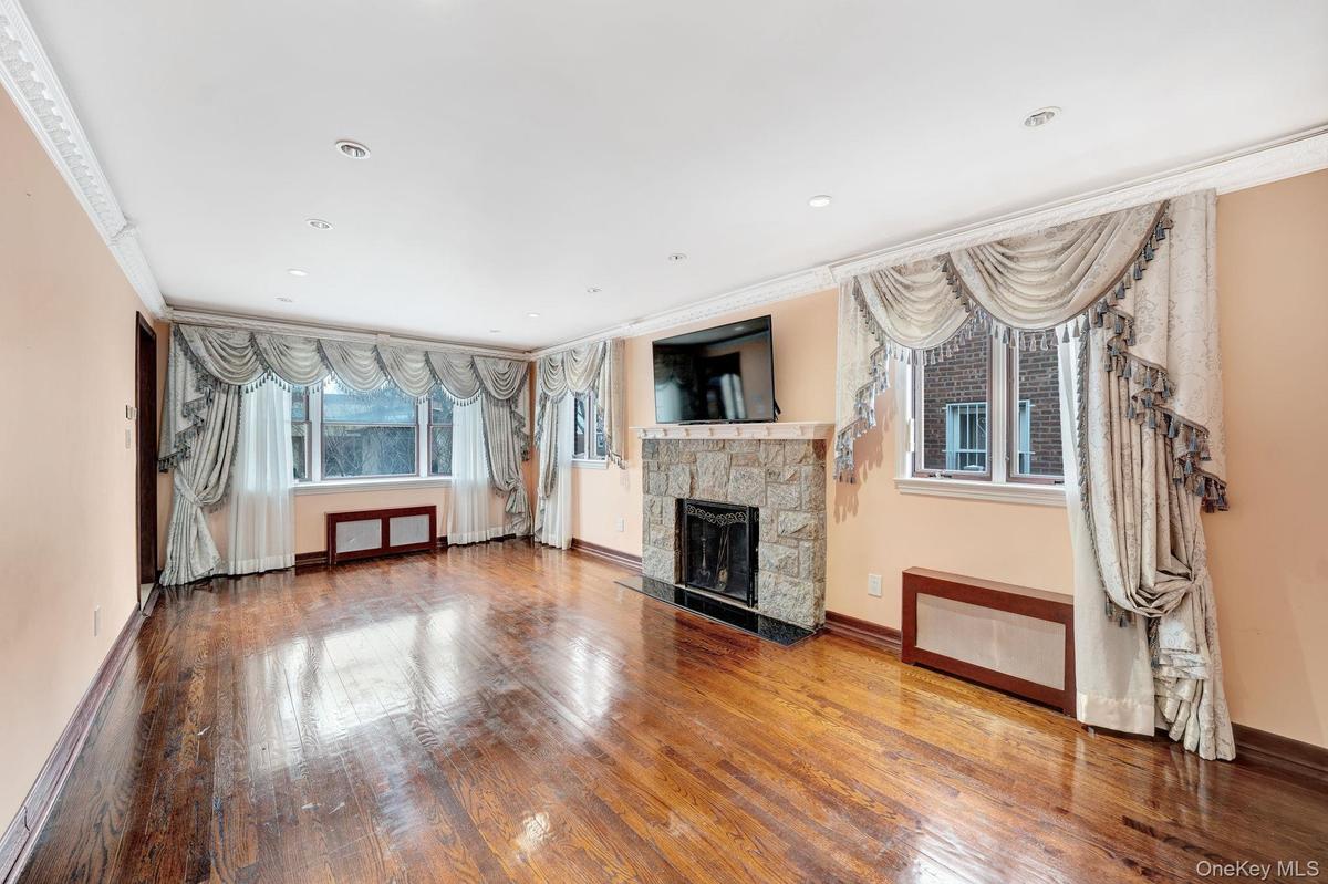 Unfurnished living room with a stone fireplace, wood-type flooring, recessed lighting, and crown molding