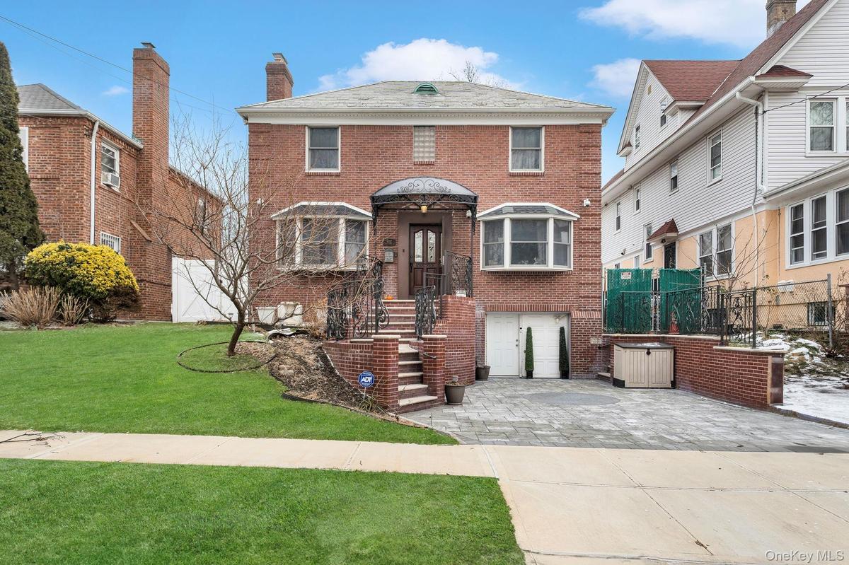 View of front of property featuring brick siding, driveway, and a chimney