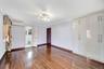 Unfurnished bedroom with a wall mounted air conditioner, connected bathroom, dark wood-style floors, and ornamental molding