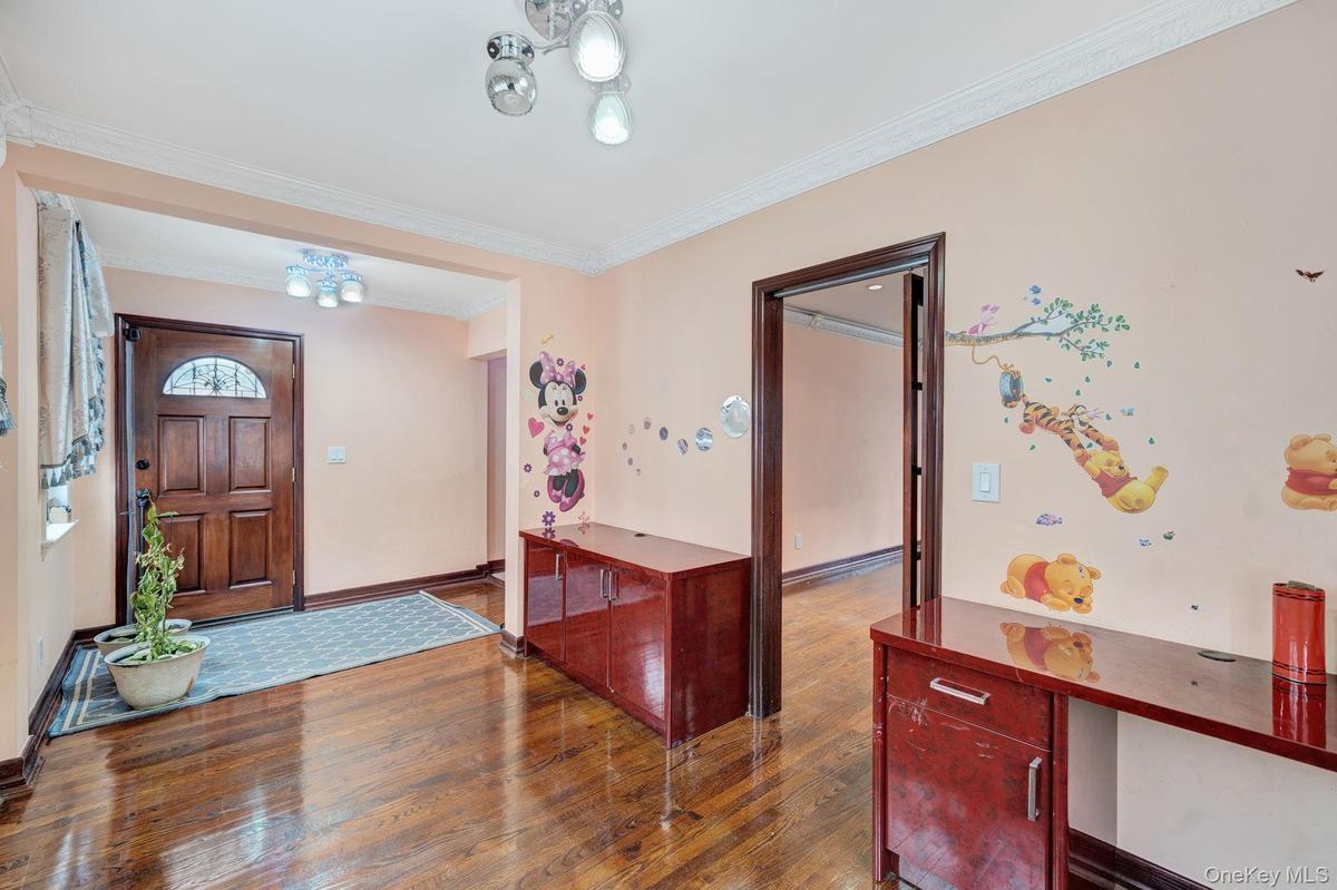 Entryway with ornamental molding, wood-type flooring, and a chandelier