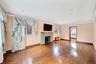 Unfurnished living room featuring a stone fireplace, hardwood / wood-style flooring, recessed lighting, ornamental molding, and an AC wall unit