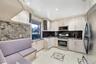 Kitchen featuring appliances with stainless steel finishes, glass insert cabinets, dark stone counters, recessed lighting, and light tile patterned fl