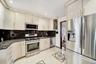 Kitchen featuring stainless steel appliances, dark stone counters, glass insert cabinets, light tile patterned floors, and decorative backsplash