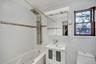 Bathroom with tile walls, a combined bath / shower with jetted tub, vanity, and ornamental molding