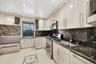 Kitchen featuring glass insert cabinets, stainless steel appliances, decorative backsplash, dark stone countertops, and recessed lighting