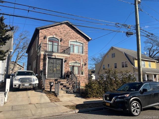 View of front of home with brick siding and a balcony