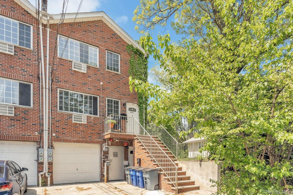 Back of house with brick siding, a garage, stairs, and concrete driveway