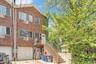 Back of house with brick siding, a garage, stairs, and concrete driveway