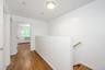 Hallway with an upstairs landing, wood-type flooring, and a baseboard heating unit