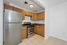 Kitchen with stainless steel appliances, light tile patterned floors, dark stone counters, and brown cabinets