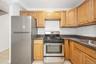 Kitchen featuring appliances with stainless steel finishes, light tile patterned flooring, and dark stone counters