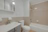 Full bathroom with vanity, shower / bathtub combination, tile walls, and a wainscoted wall