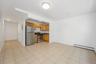 Kitchen featuring appliances with stainless steel finishes, dark countertops, a baseboard heating unit, brown cabinetry, and light tile patterned floo