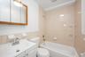 Bathroom with vanity, shower / tub combination, and tile walls
