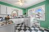 Kitchen with white range with gas stovetop, white cabinets, dark flooring, dark countertops, and crown molding
