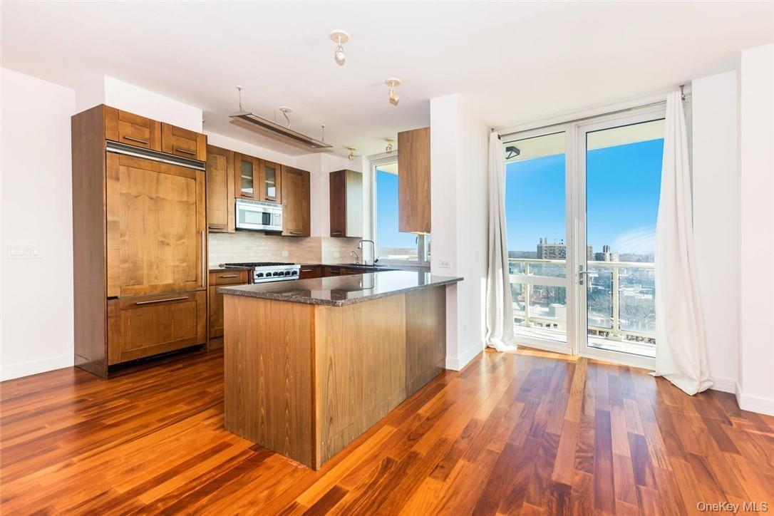 Kitchen with tasteful backsplash, sink, dark hardwood / wood-style floors, paneled refrigerator, and kitchen peninsula