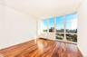 Empty room with wood finished floors, baseboards, a view of city, and floor to ceiling windows