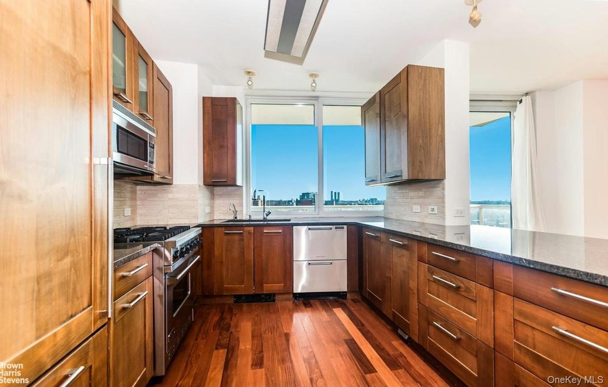 Kitchen with stainless steel appliances, dark wood-style floors, backsplash, and dark stone counters