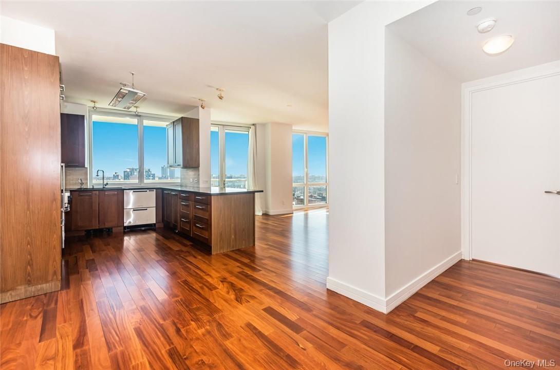 Kitchen featuring plenty of natural light, decorative backsplash, kitchen peninsula, and dark wood-type flooring