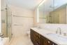 Full bathroom featuring tile walls, a shower stall, toilet, and double vanity