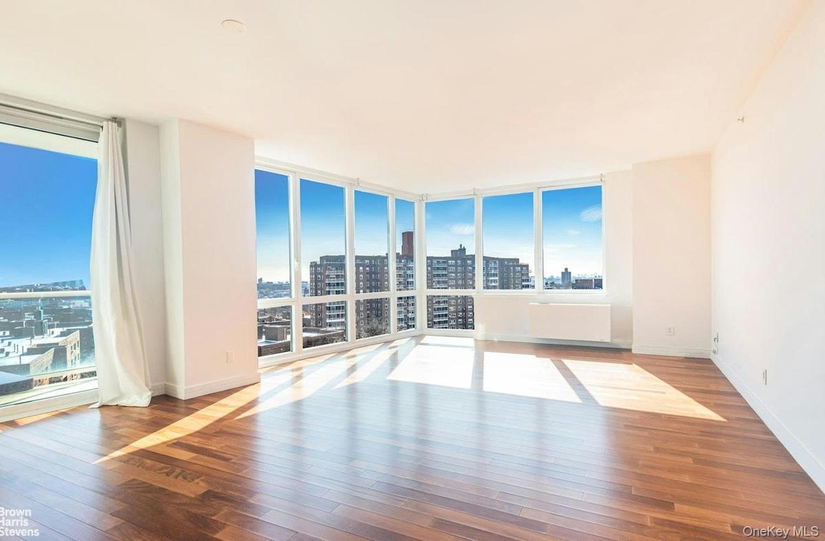 Spare room featuring a view of city, hardwood / wood-style floors, floor to ceiling windows, and baseboards