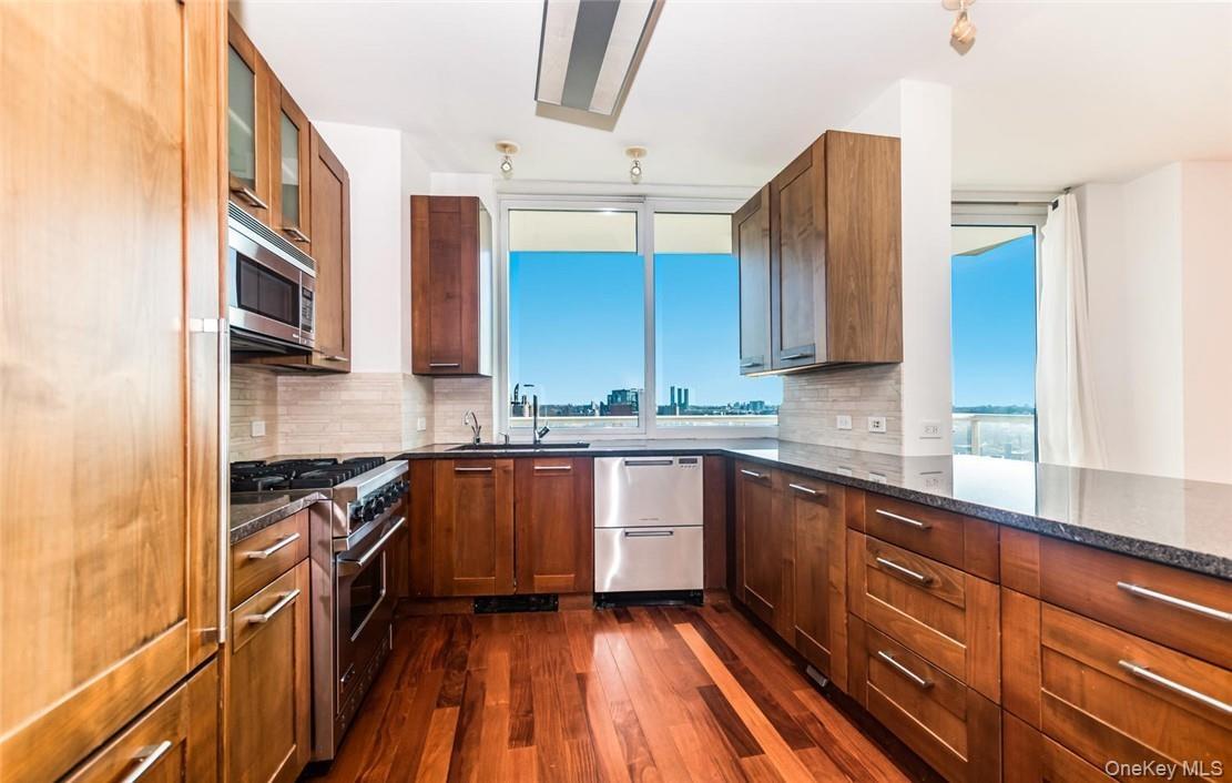 Kitchen featuring decorative backsplash, dark wood-type flooring, stainless steel appliances, and a wealth of natural light