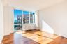 Unfurnished room featuring wood-type flooring, radiator heating unit, floor to ceiling windows, a city view, and baseboards