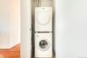 Washroom with stacked washer and clothes dryer, light wood-style flooring, and baseboards
