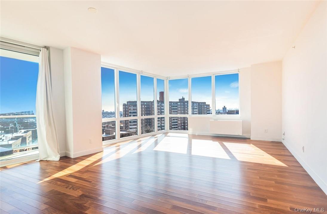 Unfurnished room featuring radiator heating unit, floor to ceiling windows, and hardwood / wood-style floors