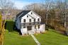 View of front of home with a porch, a standing seam roof, a front lawn, a metal roof, and a shingled roof