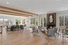 A dramatic great room with soaring ceilings, wide plank white oak floors, and walls windows framing panoramic waterfront vistas