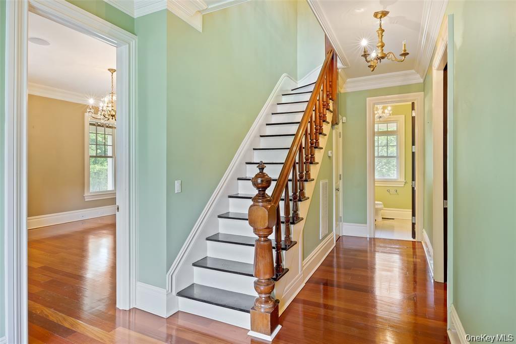 Staircase with a chandelier, crown molding, and hardwood / wood-style flooring