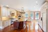 Kitchen with decorative light fixtures, backsplash, light stone counters, high quality appliances, and dark wood finished floors