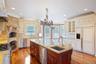 Kitchen featuring decorative backsplash, glass insert cabinets, stainless steel appliances, light stone countertops, and decorative light fixtures