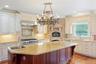 Kitchen featuring backsplash, cream cabinetry, light stone counters, light wood-style flooring, and hanging light fixtures
