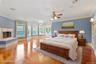 Bedroom featuring ornamental molding, a multi sided fireplace, light wood-style floors, a chandelier, and ceiling fan