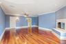 Unfurnished living room with dark wood-type flooring, ornamental molding, ceiling fan, and a fireplace