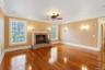 Unfurnished living room featuring hardwood / wood-style floors, ceiling fan, ornamental molding, and a fireplace