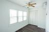 Unfurnished bedroom with dark wood finished floors, a wall unit AC, a ceiling fan, and a closet