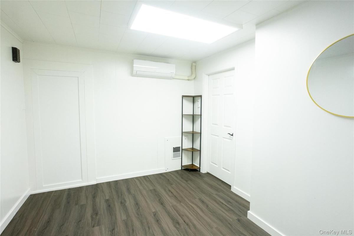 Spare room featuring dark wood-type flooring and a wall mounted air conditioner