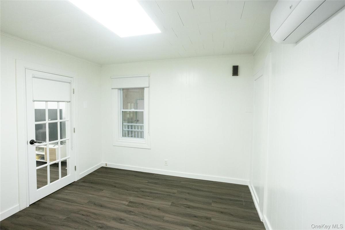 Spare room featuring dark wood-style flooring, a wall mounted air conditioner, and ornamental molding