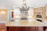 Kitchen featuring crown molding, a kitchen island, tasteful backsplash, light stone countertops, and decorative light fixtures