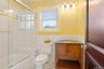 Full bathroom featuring vanity, tile walls, a wainscoted wall, combined bath / shower with glass door, and dark tile patterned floors