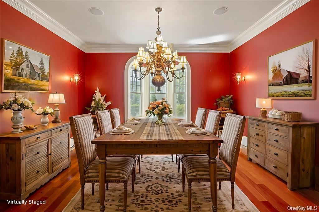 Dining space with wood finished floors, crown molding, and a chandelier